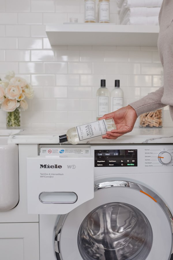 Pouring The Laundress Wool & Cashmere Shampoo into dispenser of washing machine