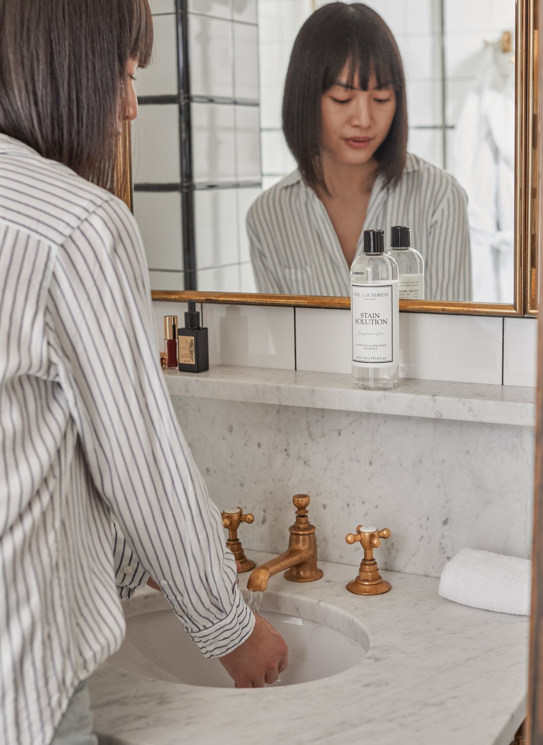 woman filling sink for a laundry soak with the laundress stain solution in background