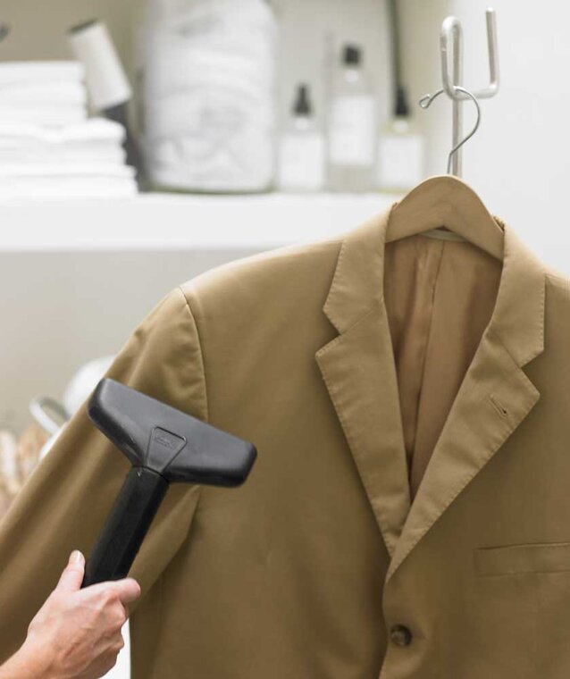 A tan jacket is steamed using The Laundress's expert method for cleaning a blazer. 