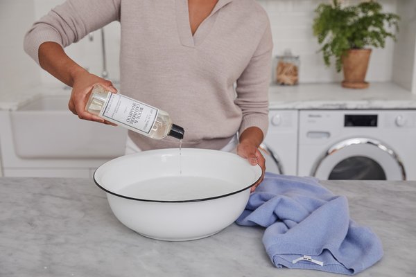 pouring the laundress wool and cashmere shampoo in white enamel basin