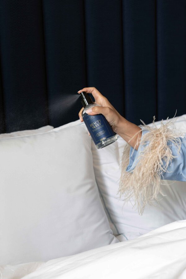 The Laundress Beauty Sleep Fabric Spray for sleepwear and bedding is spritzed onto a white pillow. 