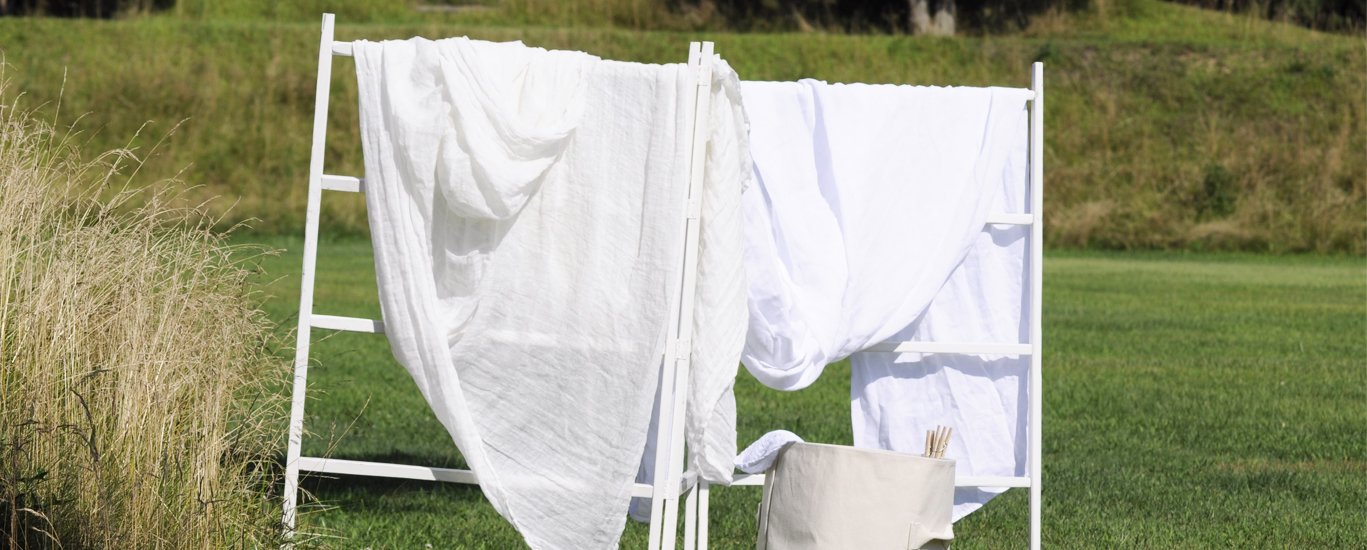 Linen material hanging on drying rack in a grassy field.