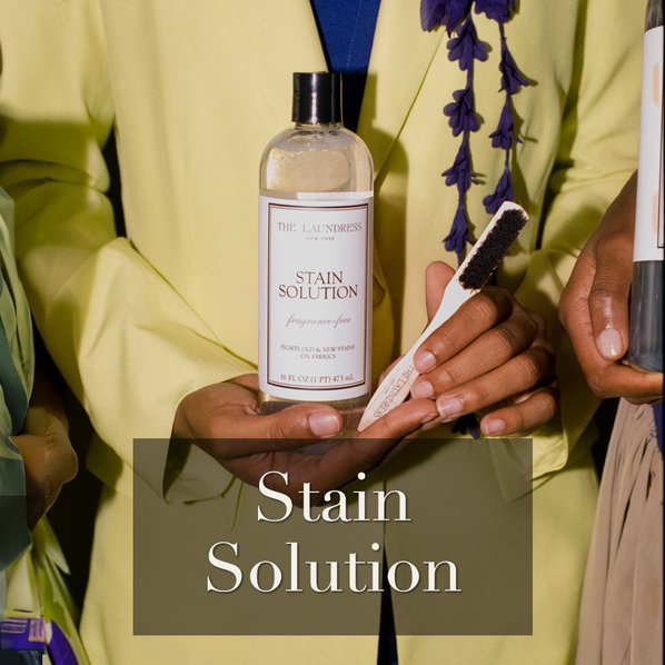 The Laundress fragrance free Stain Solution being held alongside The Laundress Stain Brush.