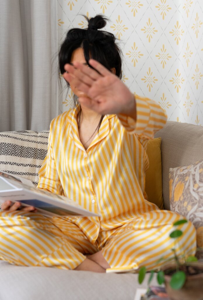 Mom sitting in her pyjama, hiding her face with her hand and looking at photo book.