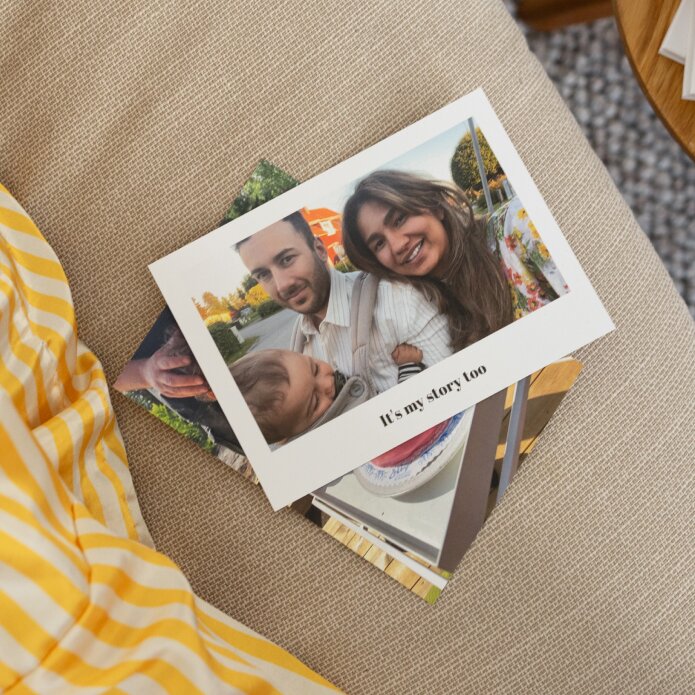 Pile of photo prints with top print shows a family and a "It's my story too" text.