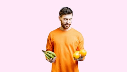 man holding fruit with pink background