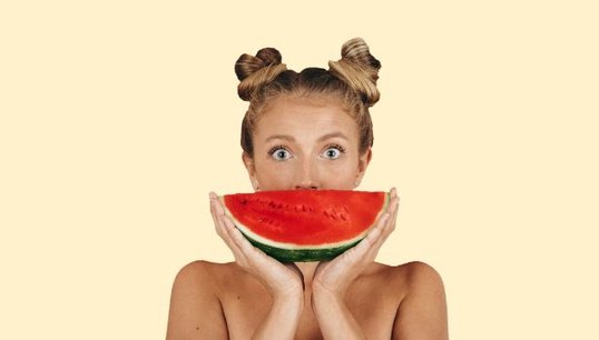 man holding 2 oranges with pink background