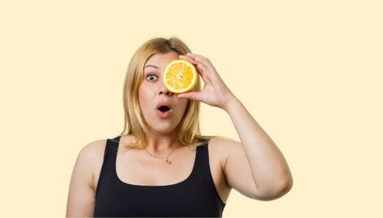 man holding 2 oranges with pink background