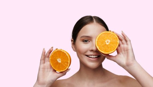 man holding 2 oranges with pink background