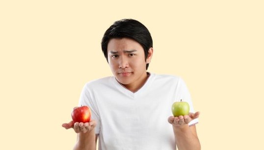 man holding two apples with orange background