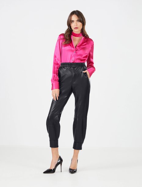 Woman in black faux leather joggers with a shiny pink blouse