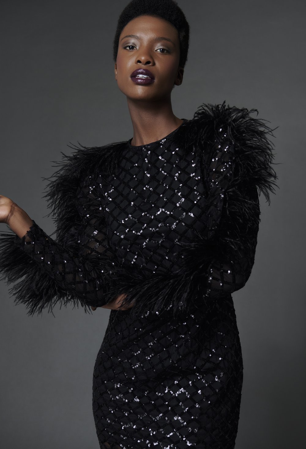 woman in black sequin mini dress with black feathers down the long sleeves