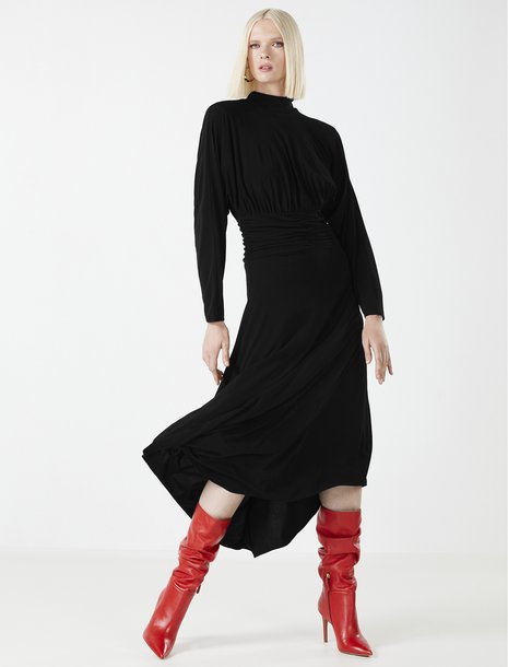 Picture of a women in black turtleneck dress with bright red slouchy boots