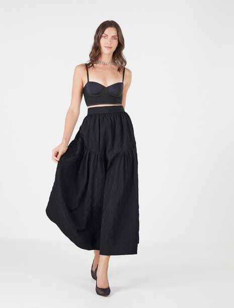 Woman wearing a black bralette with a black midi high waisted skirt