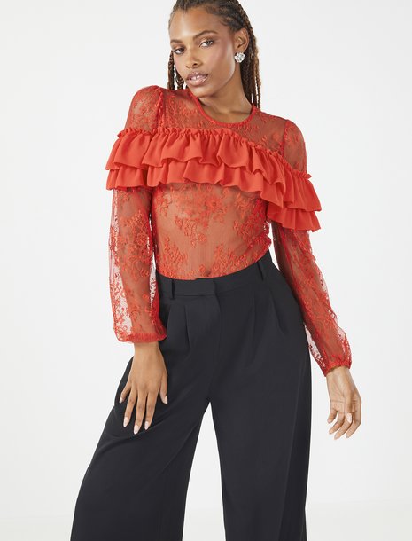 Picture of a women in black trousers and a red lace top with ruffles