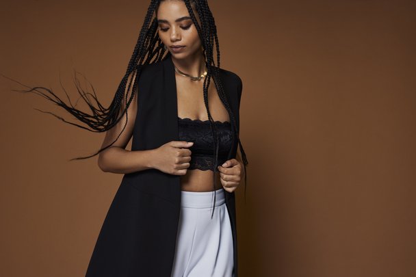 woman in black longline blazer with black lace bandeau top and light blue trousers