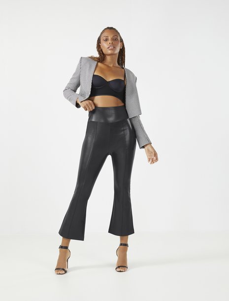 Picture of a women in pleather flare pants, a black bra top, and a cropped blazer