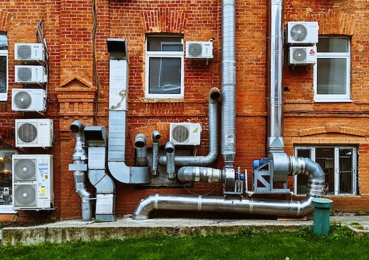 multiple air ducts and vents on a brick wall exterior