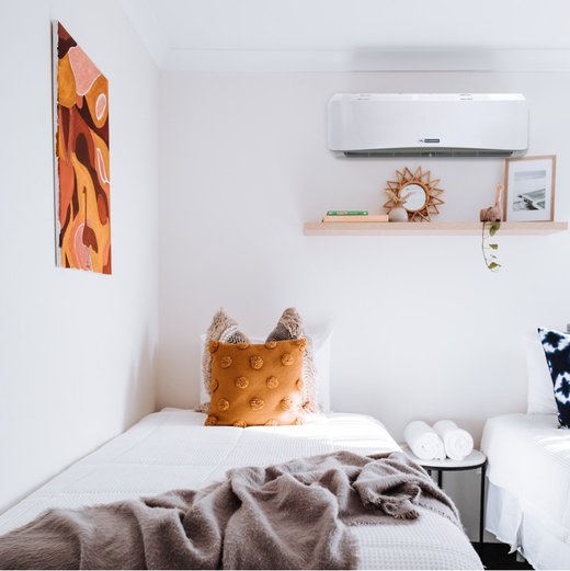 a single bedroom with a portrait, comfortable bedding, a wooden wall desk, and a blueridge mini split AC