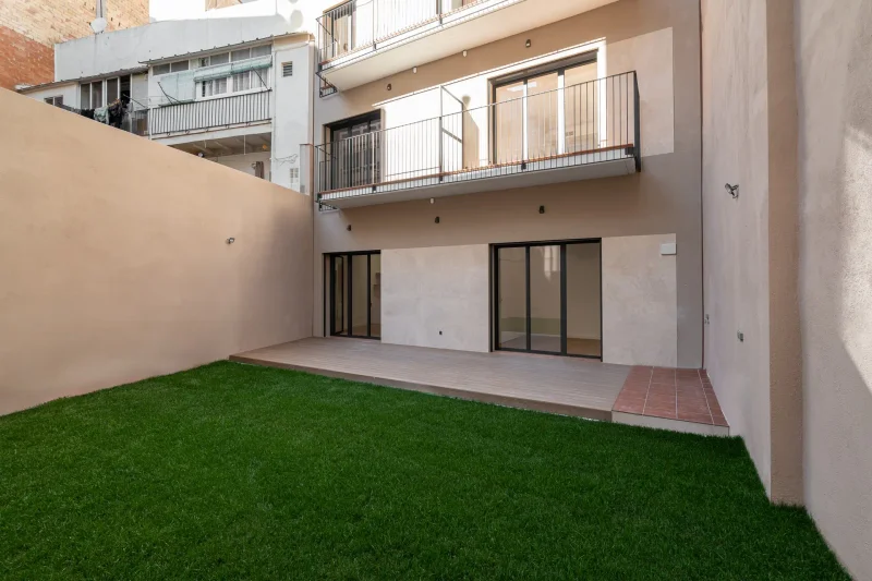Patio interior con jardín, césped y fachada con balcones