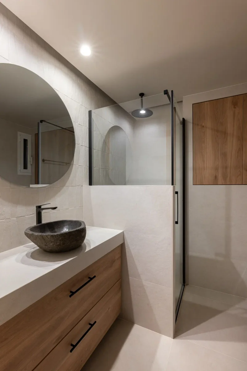 Baño moderno con ducha de cristal, lavabo de piedra y madera