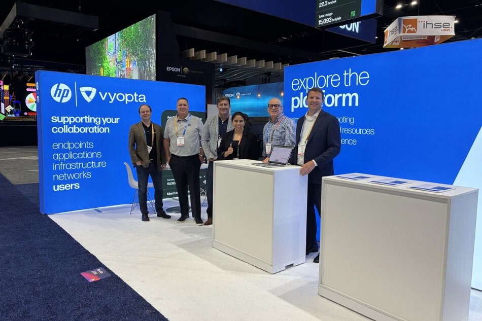 Exhibitors standing in a blue branded trade show booth with backlit displays