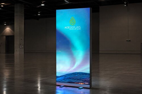 Lumos backlit banner stand with northern lights design and Ace Displays logo in dark empty warehouse reflecting on ground 