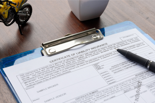 Photo of an insurance certificate on a blue clipboard on a wooden table.