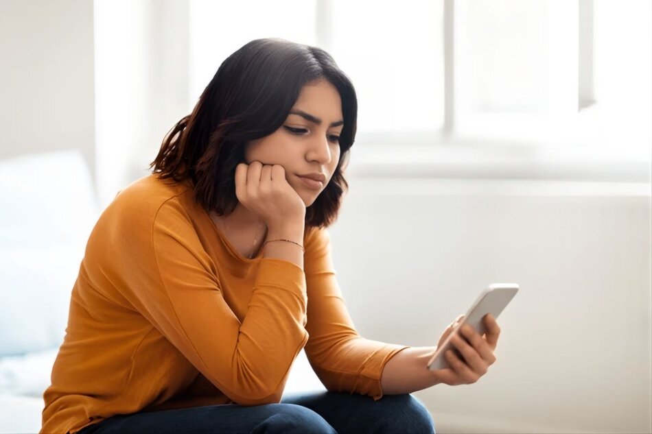 Person looking at a smartphone with a thoughtful expression