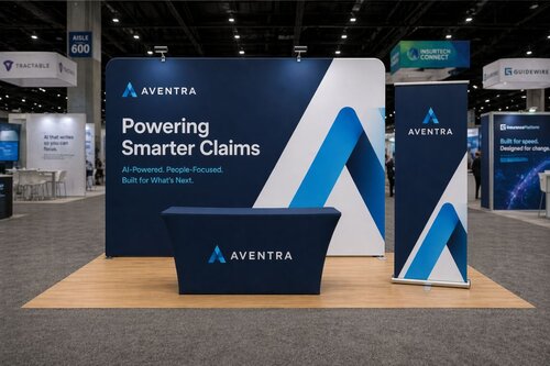 Aventra 10x10 trade show booth with clean layout featuring navy blue curved tension fabric backdrop displaying 'Powering Smarter Claims' headline, matching table cover, retractable banner stand, and minimal furniture on light wood flooring