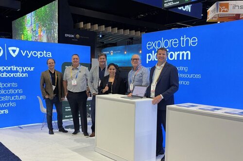 A group of people standing in front of their trade show booth with Lumos backlit displays from Ace Displays behind them.