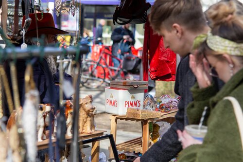 Young adults looking through a crowded outdoor event booth with handmade knick-knacks on display
