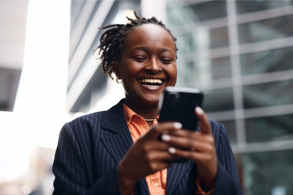 Person smiling while looking at a smartphone outdoors