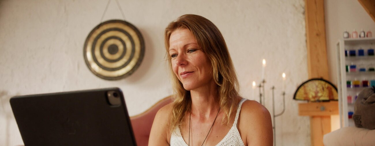 Daniela is working on her Laptop in a serene setting with candlelight.
