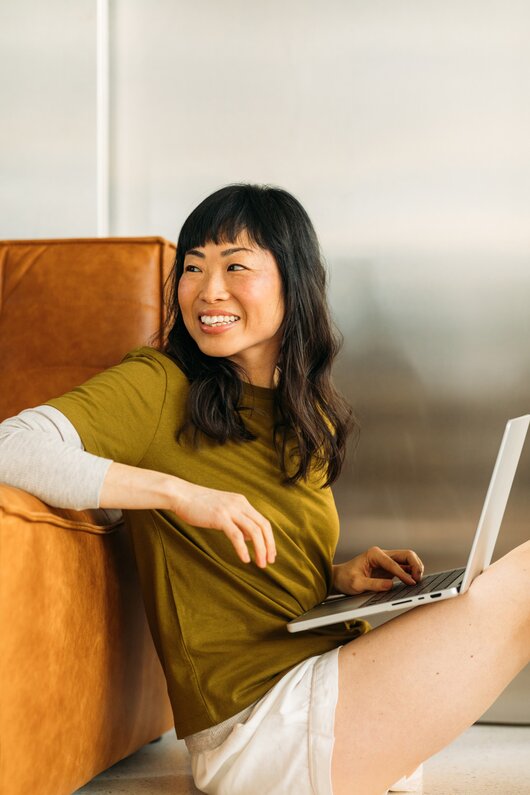 Solopreneur working on her laptop, smiling.