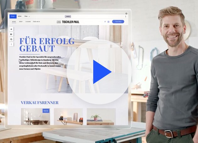 Lächelnde Person in einem Workshop neben einem Monitor, der eine Website mit Möbelentwürfen und einem großen Play-Button-Overlay anzeigt.