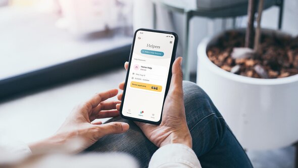 A person uses the Herewith app on their phone to view a Help Request listing and review applicants.