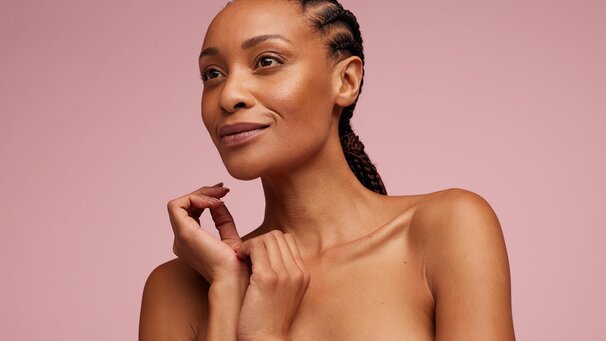 A woman is shown in a close-up portrait looking slightly to the side. Her hands are raised near her face.