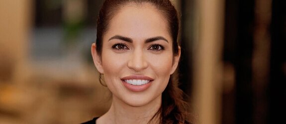 Veronica Baiz, founder of Herewith, smiling warmly in a softly lit room