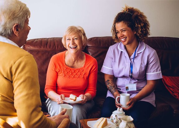 A Helper assists a senior woman with reading and daily engagement activities at home. Herewith provides flexible in-home senior care focused on dignity, independence, and meaningful connection.