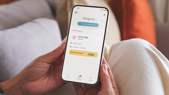 A person holds a smartphone showing a scheduled help request for home help and a button to review applicants.