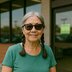 A woman with braided pigtails and sunglasses stands outside a store entrance.
