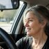 Barbara smiles and looks out her car window. Natural light comes through the window.