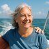 A woman smiles while sitting on a boat with a hand resting on her shoulder.