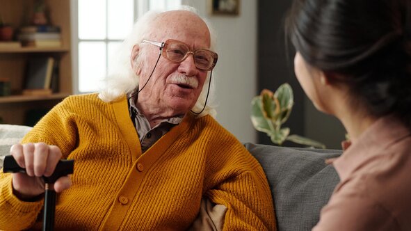 An older adult sharing a conversation at home with a Helper. Herewith provides trusted in-home senior care and companionship in Fort Worth.