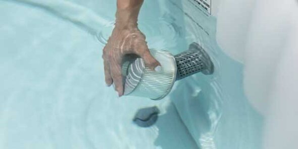 Hand entfernt einen Filtereinsatz aus der Wasserzirkulation eines Pools oder Whirlpools.