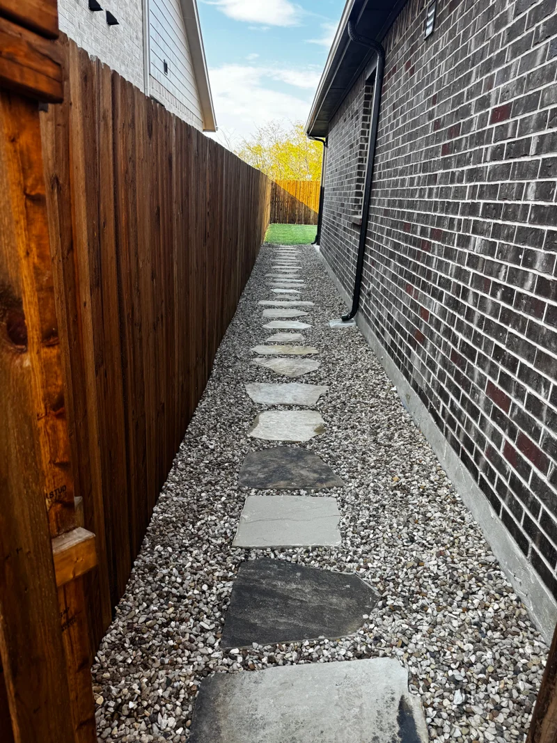 Finished gravel pathway with stepping stones beside a cedar fence