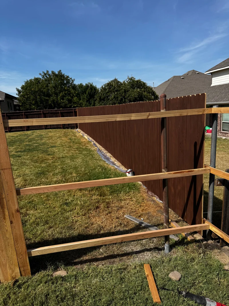 Framed gate opening being built beside a privacy fence