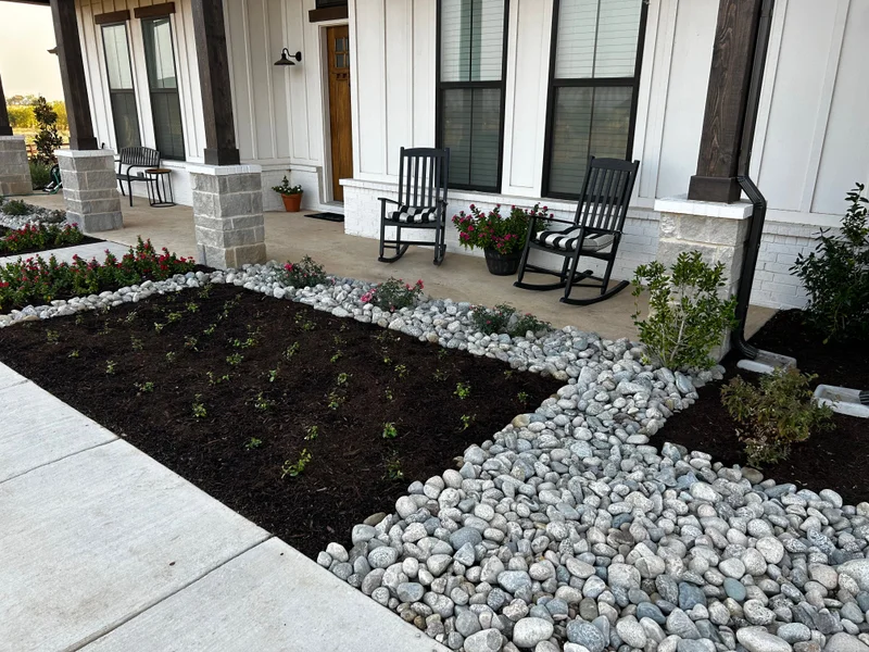 Front planting bed framed with river rock and flowering plants