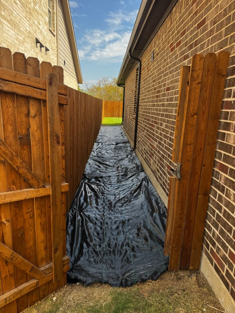 Fence-side pathway being prepared with landscape fabric